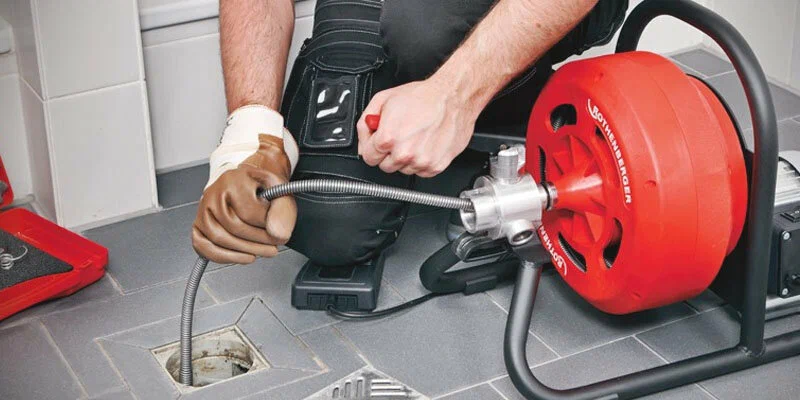 Plumber using a drain-cleaning machine in Edgewater