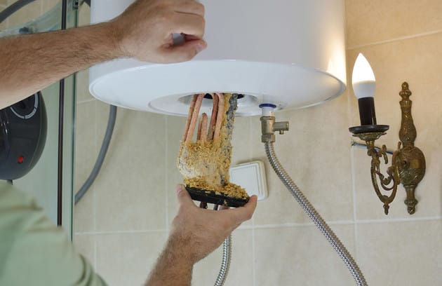 Technician removing mineral buildup from a water heater in Edgewater