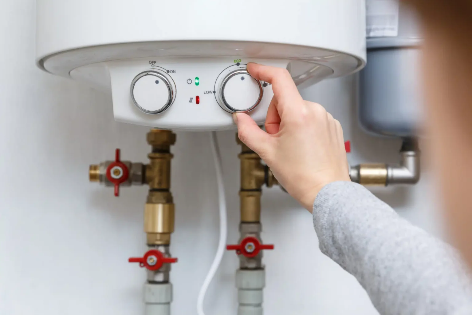 Homeowner adjusting the temperature controls on a water heater in Edgewater